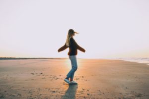 woman standing on sand near seashore during golden hour